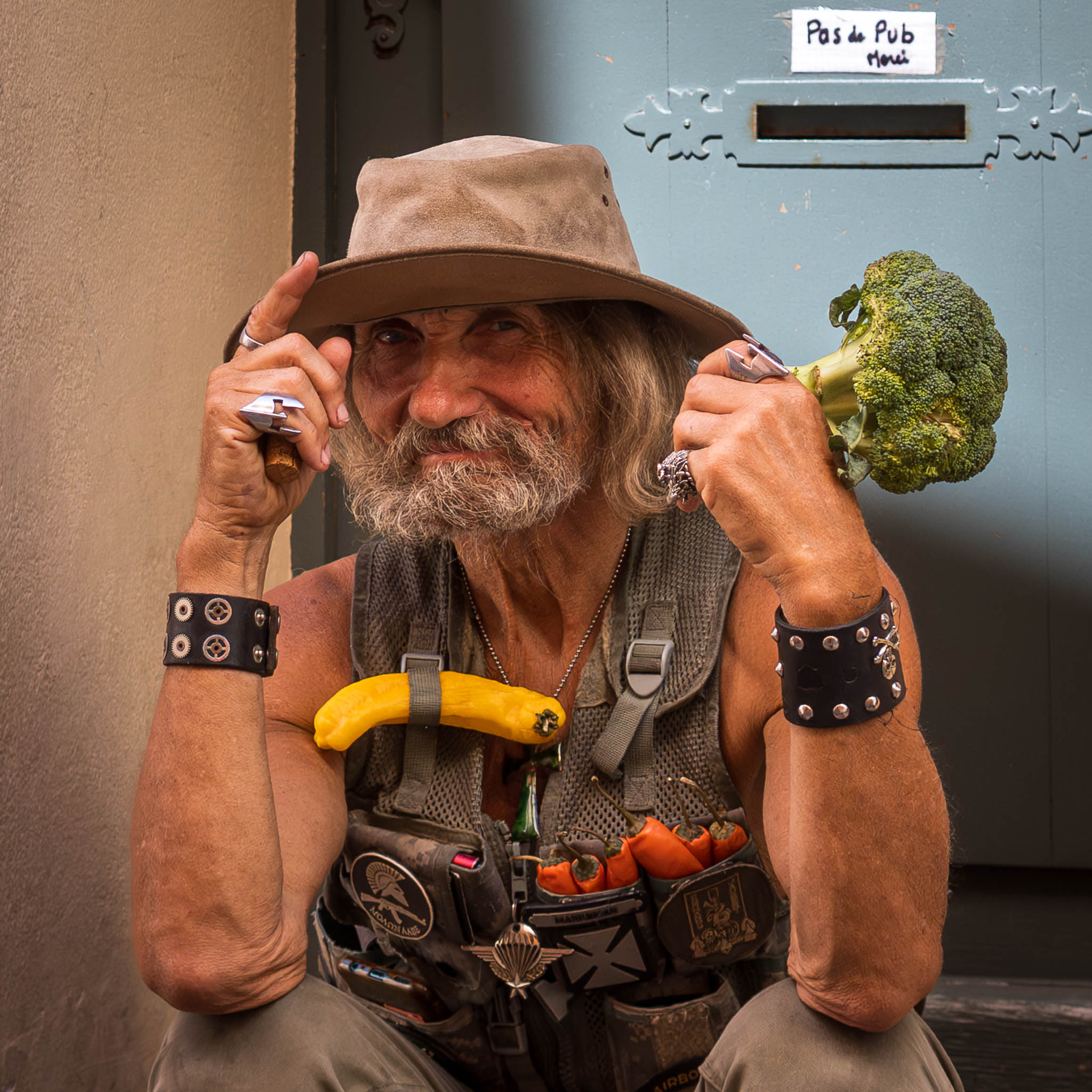 St Tropez Street Portrait eines alten Mannes mit schelmischen Lächeln und einem Brokkoli in der Hand